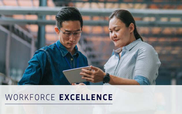 Two professionals stand together looking at a tablet, discussing work in an industrial or office setting. Text overlay reads "Workforce Excellence.