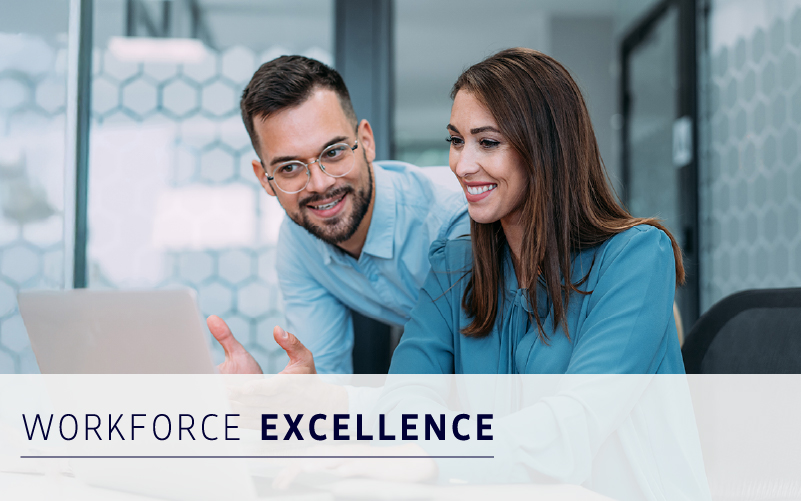 Two professionals in blue shirts smiling and looking at a laptop screen in a modern office, with the text "WORKFORCE EXCELLENCE" displayed at the bottom.
