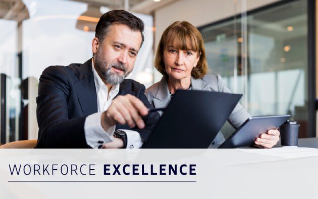 Two business professionals sit at a table with a laptop and tablet, discussing work in an office. Text reads "Workforce Excellence.
